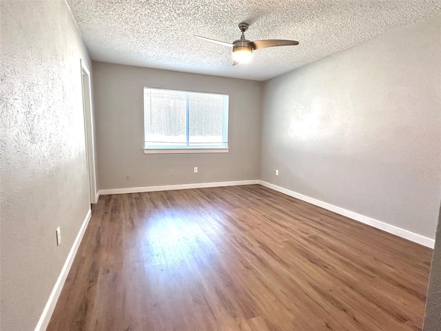 unfurnished room with a textured ceiling, dark hardwood / wood-style flooring, and ceiling fan