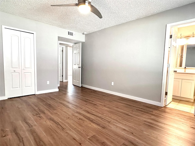 unfurnished bedroom with a textured ceiling, a closet, ceiling fan, and connected bathroom