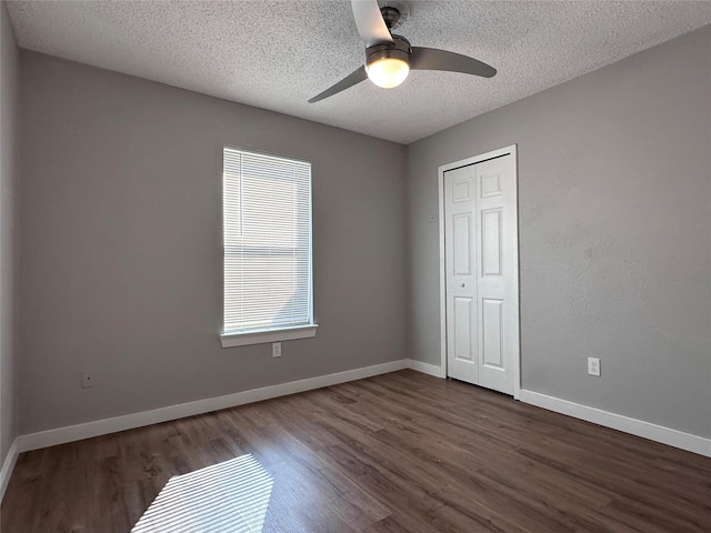 unfurnished bedroom featuring ceiling fan, a closet, dark hardwood / wood-style floors, and a textured ceiling