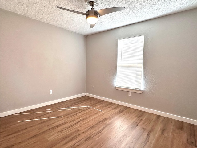 spare room with a textured ceiling, hardwood / wood-style flooring, ceiling fan, and a healthy amount of sunlight