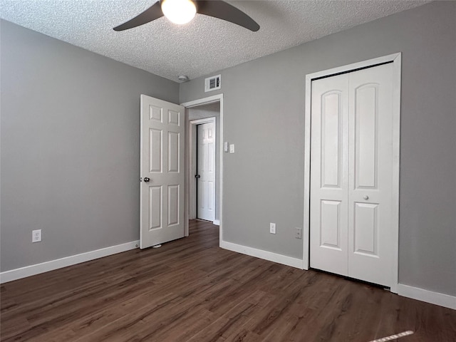 unfurnished bedroom with a textured ceiling, a closet, ceiling fan, and dark hardwood / wood-style floors