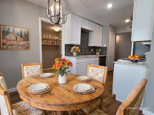 dining area with a textured ceiling, dark hardwood / wood-style flooring, an inviting chandelier, and sink