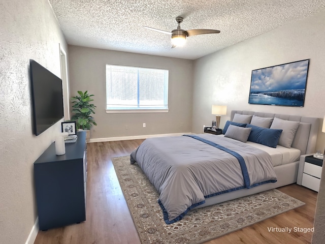 bedroom featuring ceiling fan, wood-type flooring, and a textured ceiling