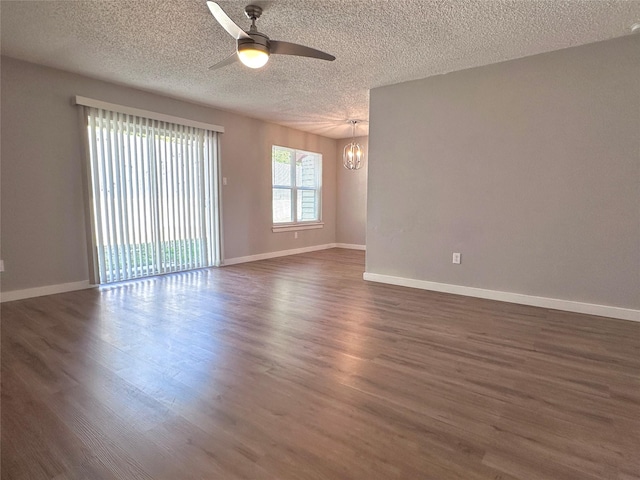 empty room featuring a textured ceiling, dark hardwood / wood-style flooring, and ceiling fan with notable chandelier