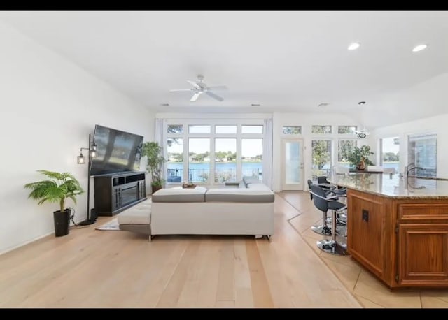 living room featuring ceiling fan with notable chandelier and light wood-type flooring