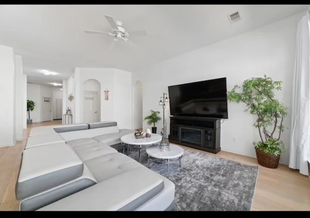 living room with light hardwood / wood-style floors, a fireplace, and ceiling fan