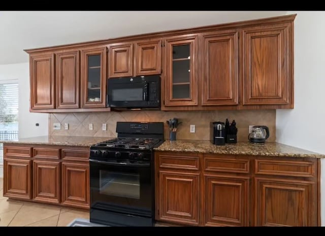 kitchen with tasteful backsplash, black appliances, light stone countertops, and light tile patterned floors