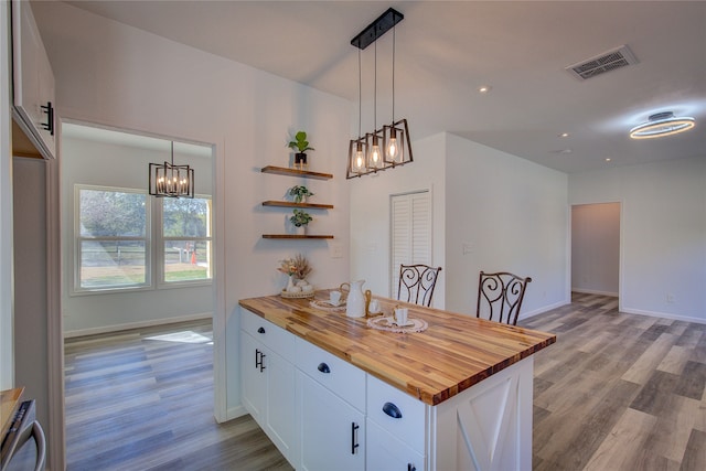 kitchen with wood counters, light hardwood / wood-style flooring, decorative light fixtures, and white cabinets