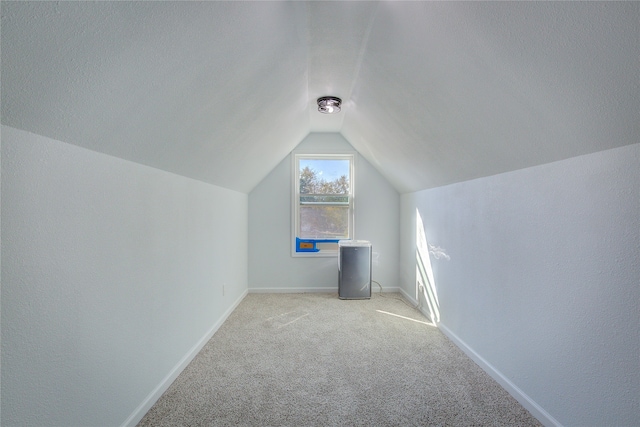 bonus room featuring lofted ceiling, a textured ceiling, and light colored carpet