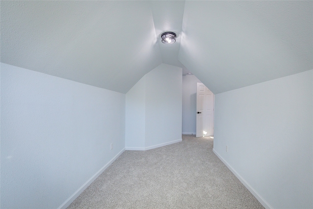 bonus room with vaulted ceiling and light carpet