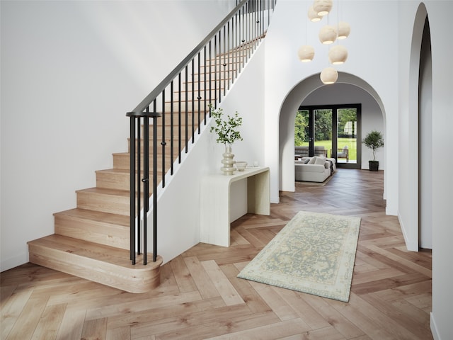 stairway featuring parquet floors, a high ceiling, and a chandelier