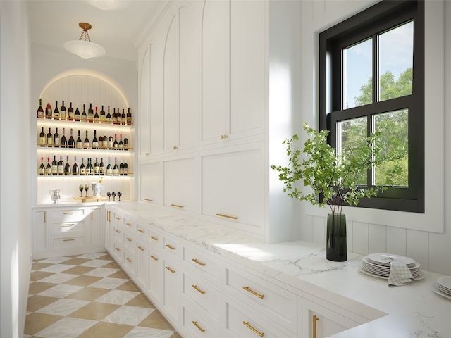 bar featuring pendant lighting, white cabinetry, and light stone countertops