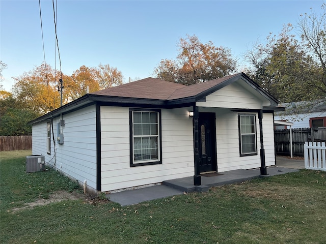 bungalow-style home featuring a front lawn and central AC unit