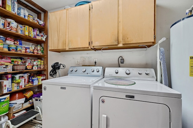 washroom with gas water heater, washing machine and dryer, and cabinets