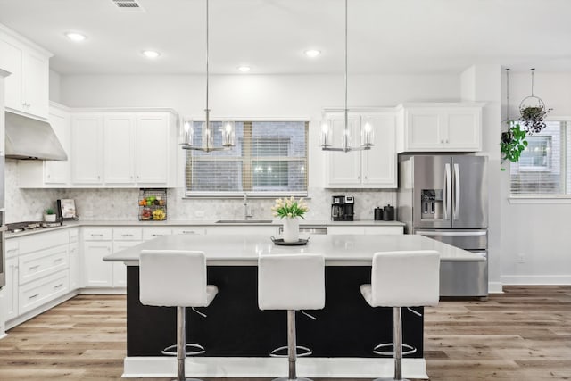 kitchen with a kitchen island, extractor fan, light hardwood / wood-style flooring, stainless steel appliances, and sink