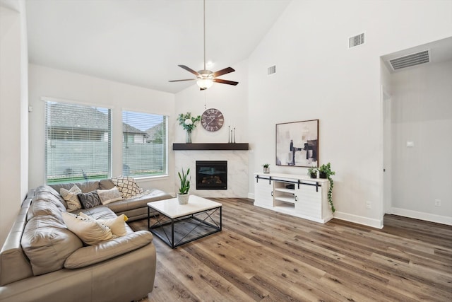 living area with high vaulted ceiling, a fireplace, visible vents, and wood finished floors