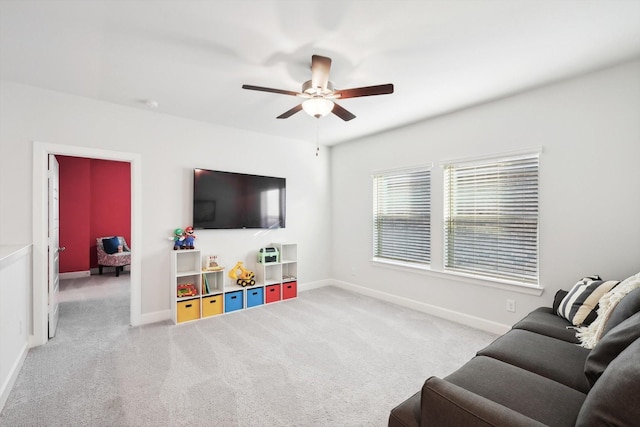 living room featuring baseboards, ceiling fan, and light colored carpet