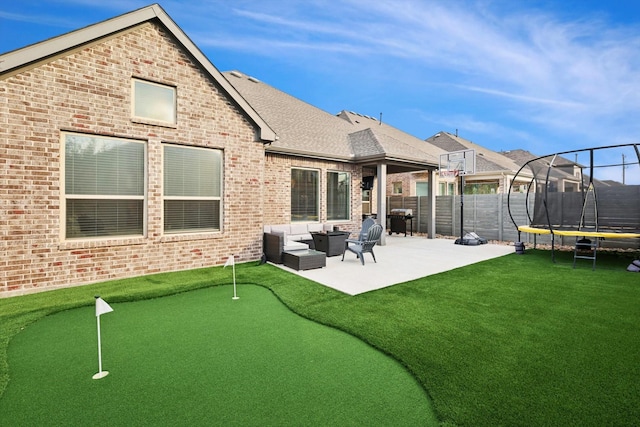 back of house featuring a patio, a trampoline, fence, an outdoor living space, and brick siding