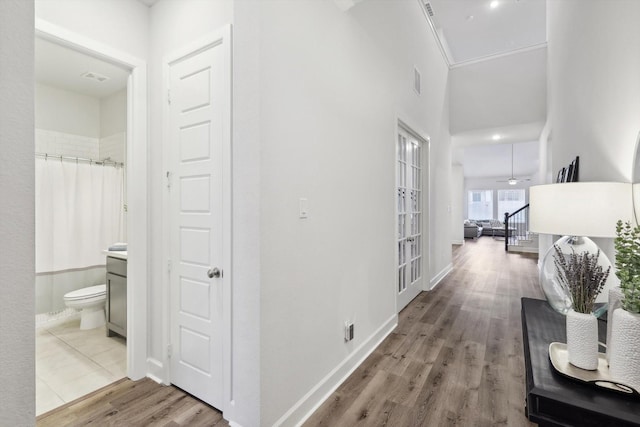 hallway featuring stairs, visible vents, baseboards, and wood finished floors