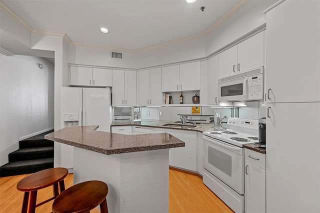 kitchen featuring white cabinets, a breakfast bar area, light wood-type flooring, sink, and white appliances