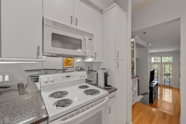 kitchen with white appliances, white cabinetry, and light hardwood / wood-style flooring