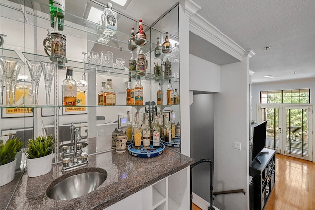 kitchen featuring sink, hardwood / wood-style floors, a textured ceiling, and dark stone counters