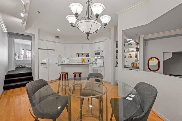 dining area featuring light hardwood / wood-style flooring, a notable chandelier, and crown molding