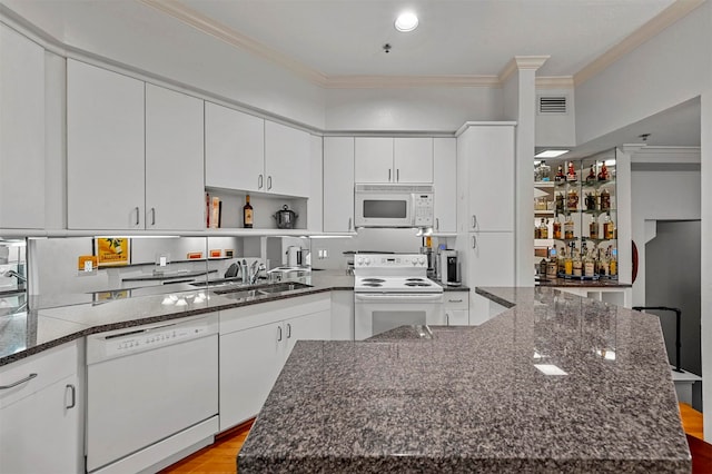 kitchen featuring white appliances, light wood-type flooring, a kitchen island, dark stone countertops, and ornamental molding