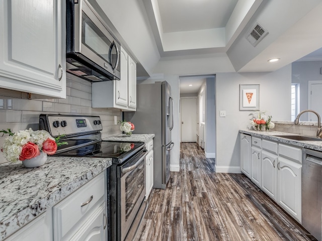 kitchen with white cabinets, tasteful backsplash, dark hardwood / wood-style floors, sink, and stainless steel appliances