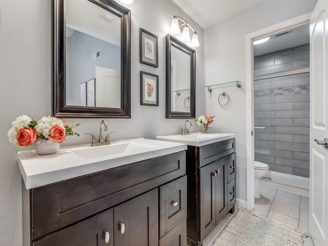 bathroom with vanity, a tile shower, and toilet