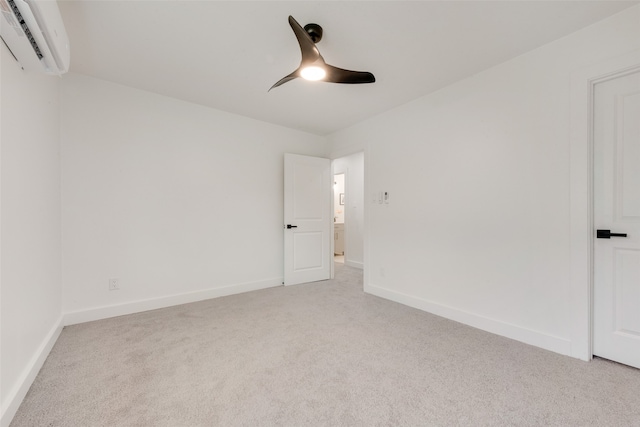 spare room with light carpet, an AC wall unit, and ceiling fan