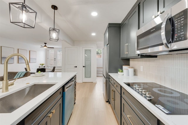 kitchen featuring pendant lighting, backsplash, sink, light hardwood / wood-style flooring, and stainless steel appliances