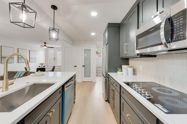 kitchen featuring pendant lighting, sink, gray cabinets, appliances with stainless steel finishes, and light wood-type flooring