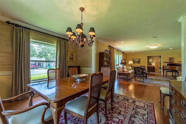 dining space with an inviting chandelier, ornamental molding, a textured ceiling, and wood-type flooring