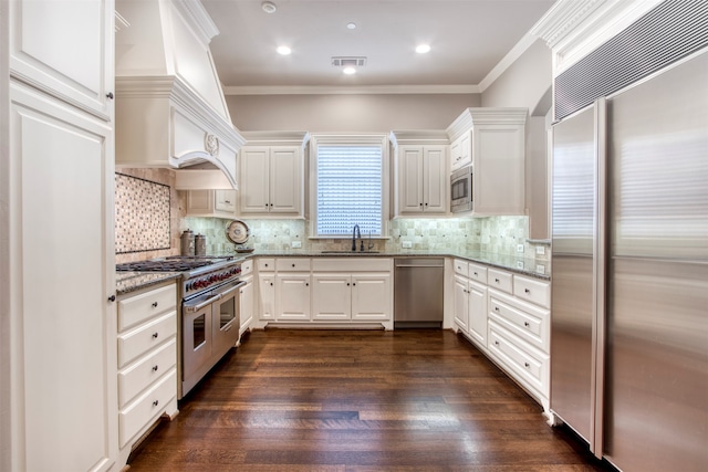 kitchen featuring dark wood-type flooring, stone countertops, built in appliances, and white cabinetry