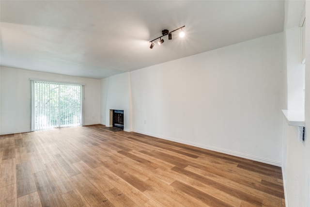 unfurnished living room featuring light hardwood / wood-style floors, track lighting, and a large fireplace