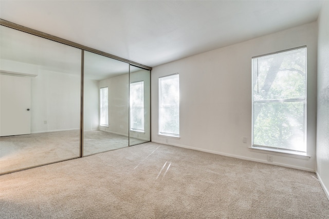 unfurnished bedroom with light colored carpet and a closet