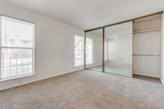 unfurnished bedroom featuring a closet and light colored carpet