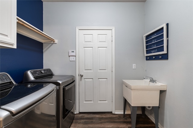 laundry room featuring dark wood-type flooring, washer and dryer, and cabinets