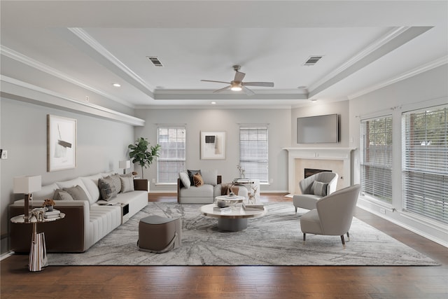 living room with crown molding, hardwood / wood-style floors, a tray ceiling, and plenty of natural light