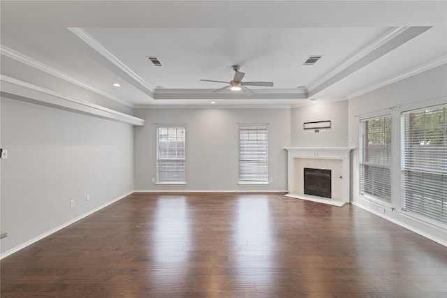 unfurnished living room with crown molding, dark wood-type flooring, plenty of natural light, and a raised ceiling