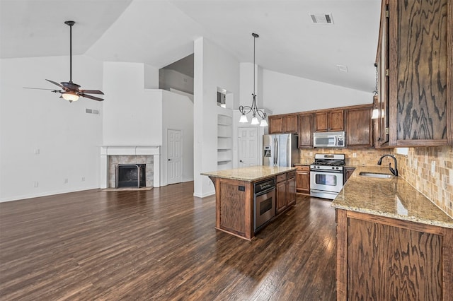 kitchen with appliances with stainless steel finishes, dark hardwood / wood-style floors, a center island, and high vaulted ceiling