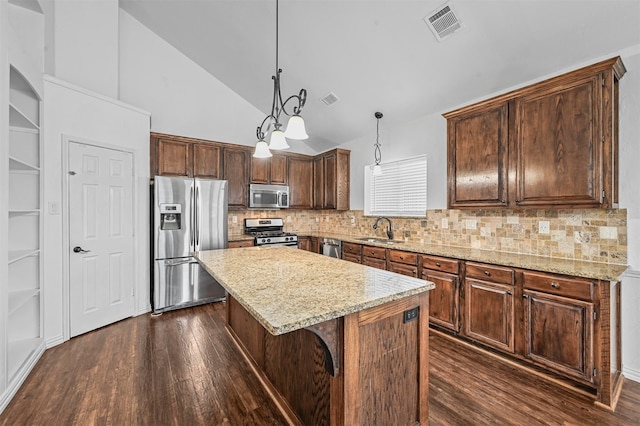 kitchen with appliances with stainless steel finishes, sink, a kitchen island, pendant lighting, and dark wood-type flooring