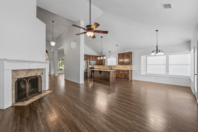 unfurnished living room featuring ceiling fan, high vaulted ceiling, a fireplace, and dark hardwood / wood-style flooring