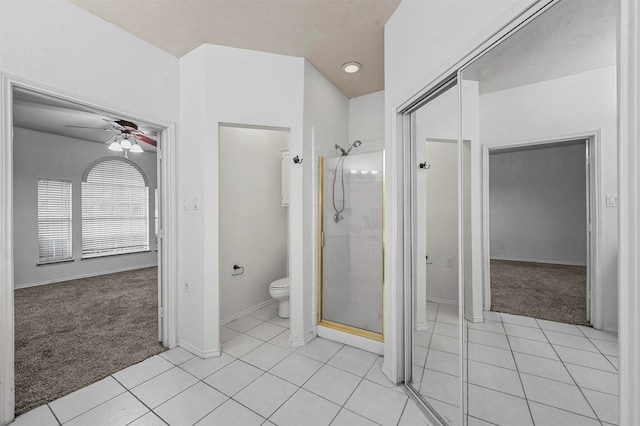 bathroom with toilet, tile patterned flooring, a shower with shower door, and ceiling fan