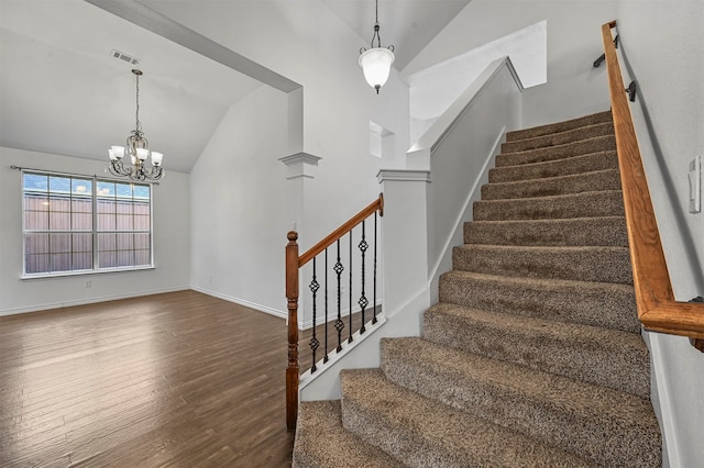 stairs featuring a chandelier, wood-type flooring, high vaulted ceiling, and decorative columns