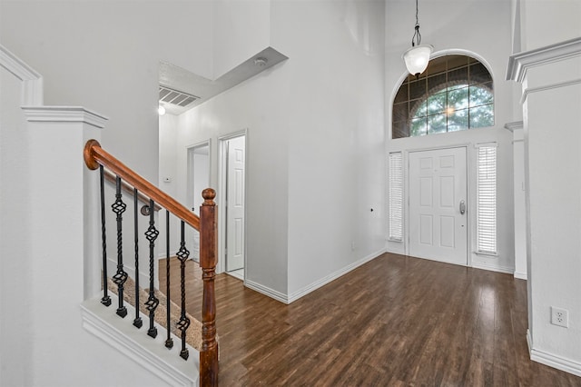 entryway featuring dark wood-type flooring and a towering ceiling