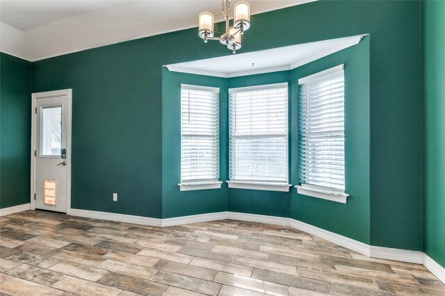 spare room featuring wood-type flooring, a notable chandelier, and ornamental molding