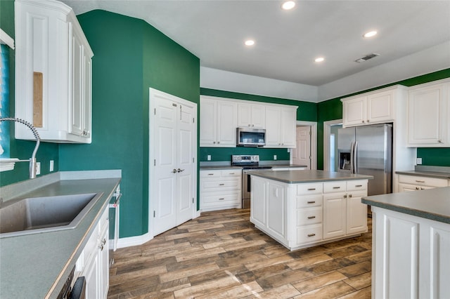 kitchen featuring white cabinets, a kitchen island, wood-type flooring, and appliances with stainless steel finishes