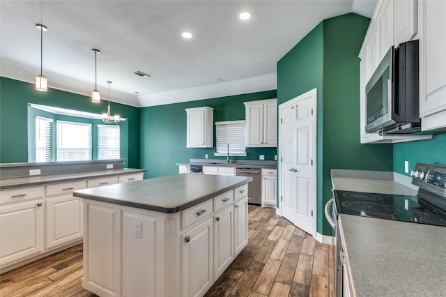 kitchen featuring a center island, stainless steel appliances, an inviting chandelier, light hardwood / wood-style floors, and white cabinets